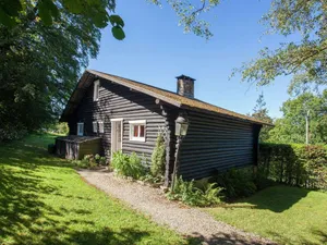 Image of Open wooden chalet built against a hill.