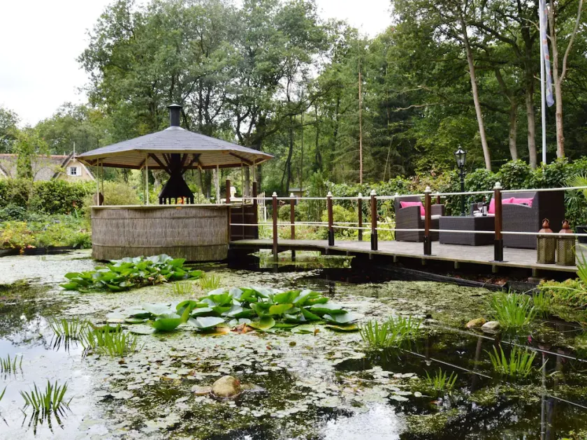A detached bungalow with outdoor fireplace, covered terrace and pond in a forest plot - Image 1