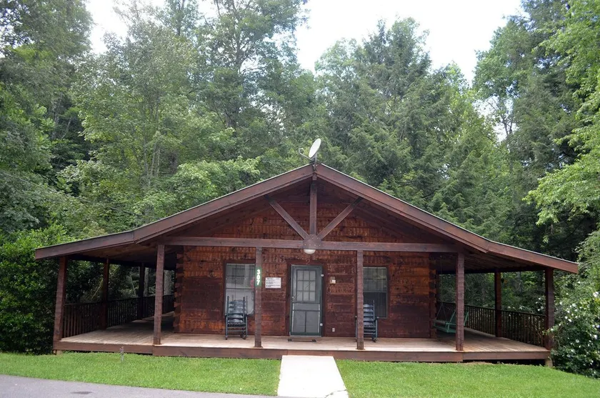 cozy cabin in the woods in a relaxing area with wrap around porch rocking chairs - Image 1