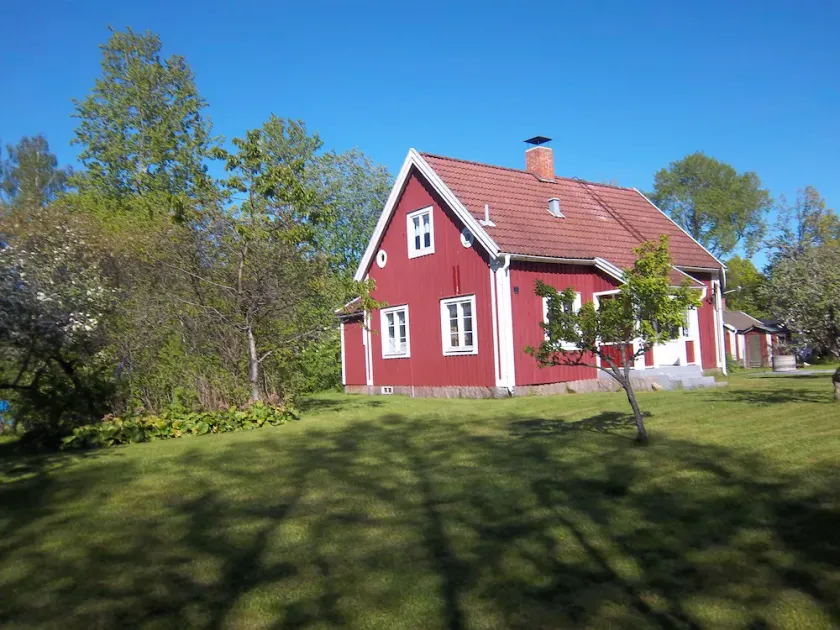 Sejlerhus rødt sommerhus nær sø og golfbane med båd i landsbyens beliggenhed - Image 1